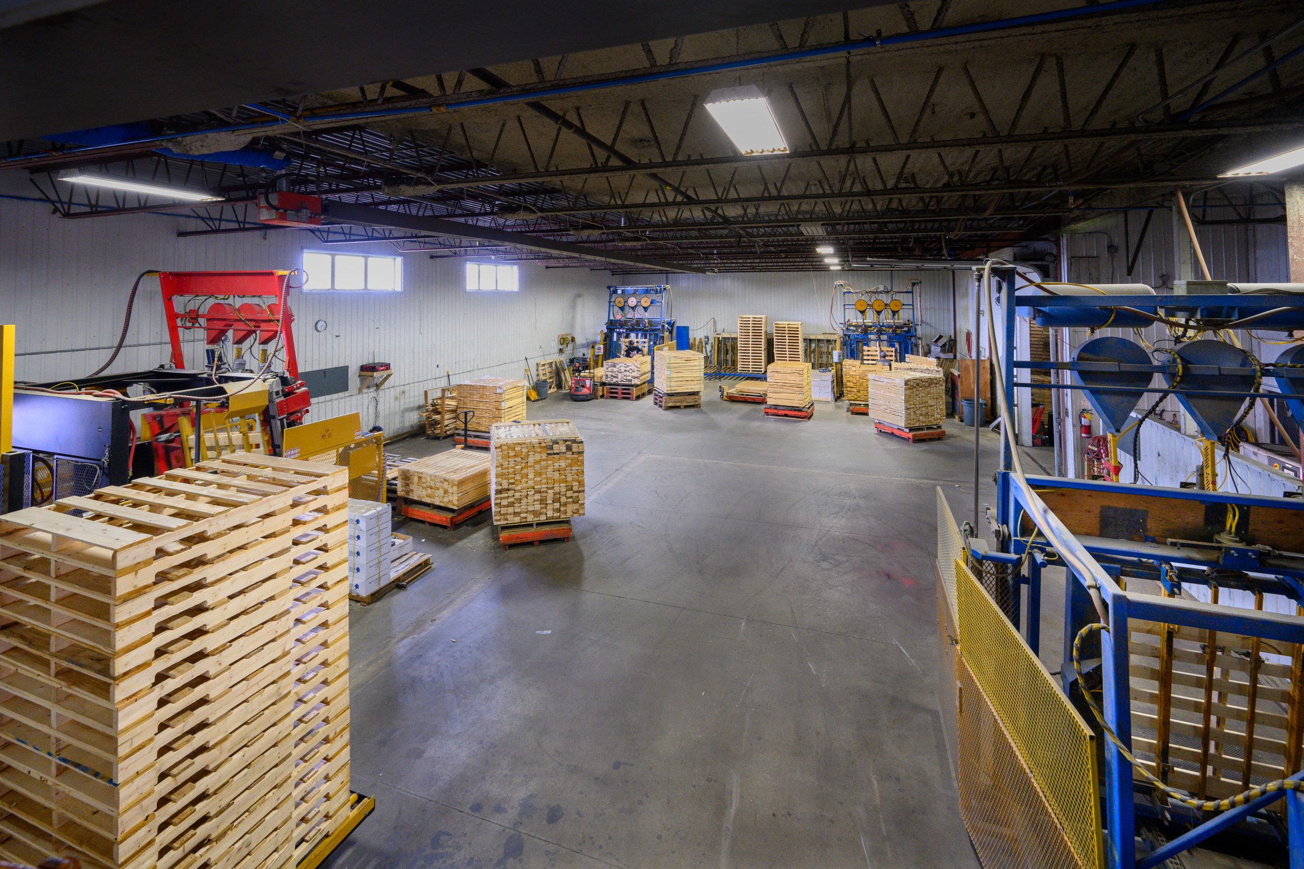 Atelier industriel avec palettes et machines.